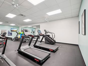 Three treadmills are lined up in a row in a gym.